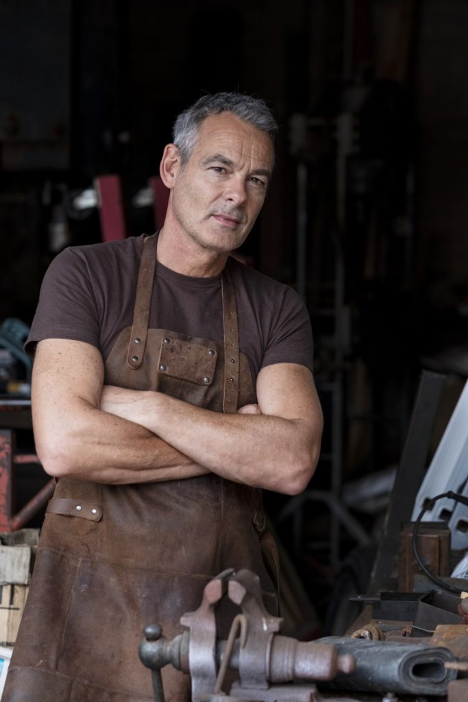 Artisan menuisier en tablier de cuir dans son atelier