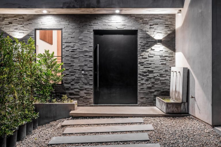 Porte d’entrée moderne noire posée sur une façade en pierre