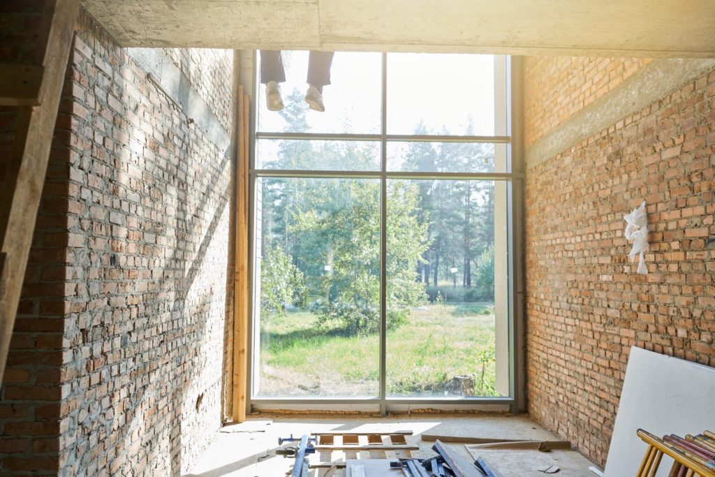 Grande fenêtre neuve posée dans une pièce en rénovation aux murs de brique