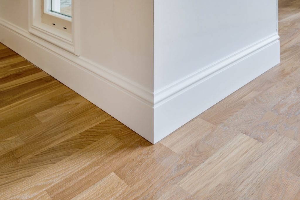 Détail d'un parquet en chêne et d'une plinthe moulurée blanche