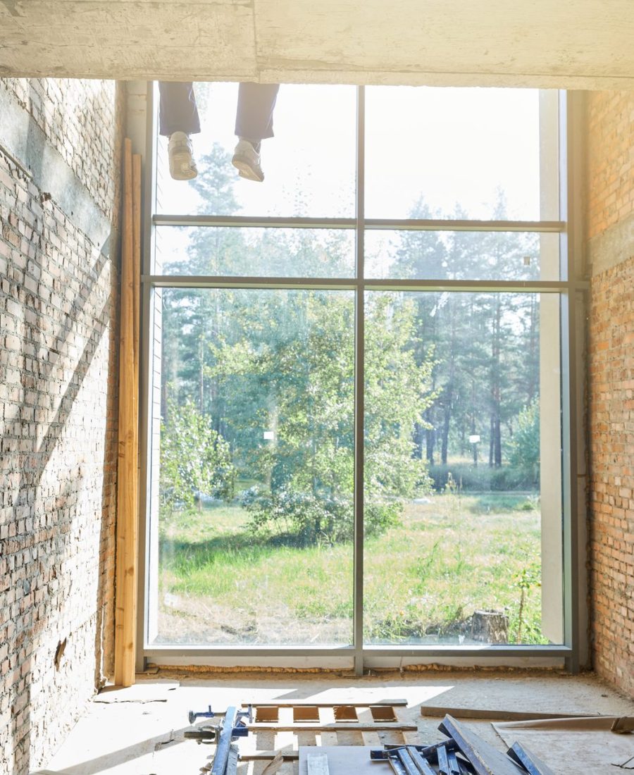 Grande fenêtre neuve posée dans une pièce en rénovation aux murs de brique